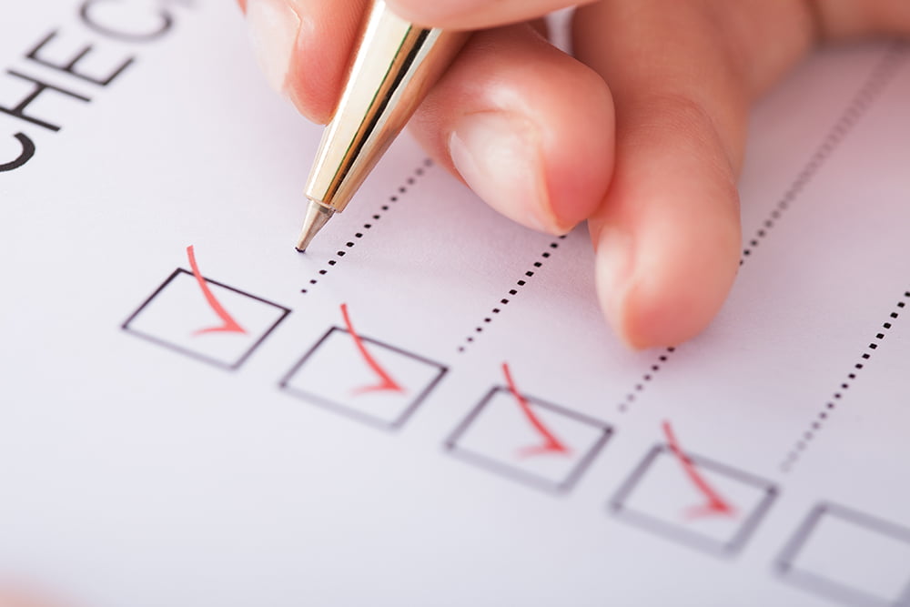 closup of hand holding pen checking off a checklist
