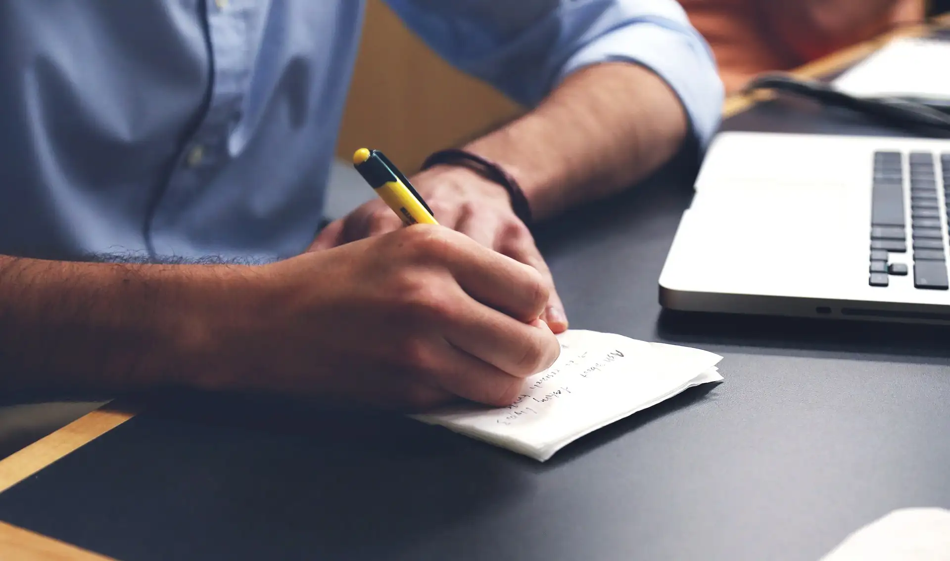 Man writing in notebook sitting at desk